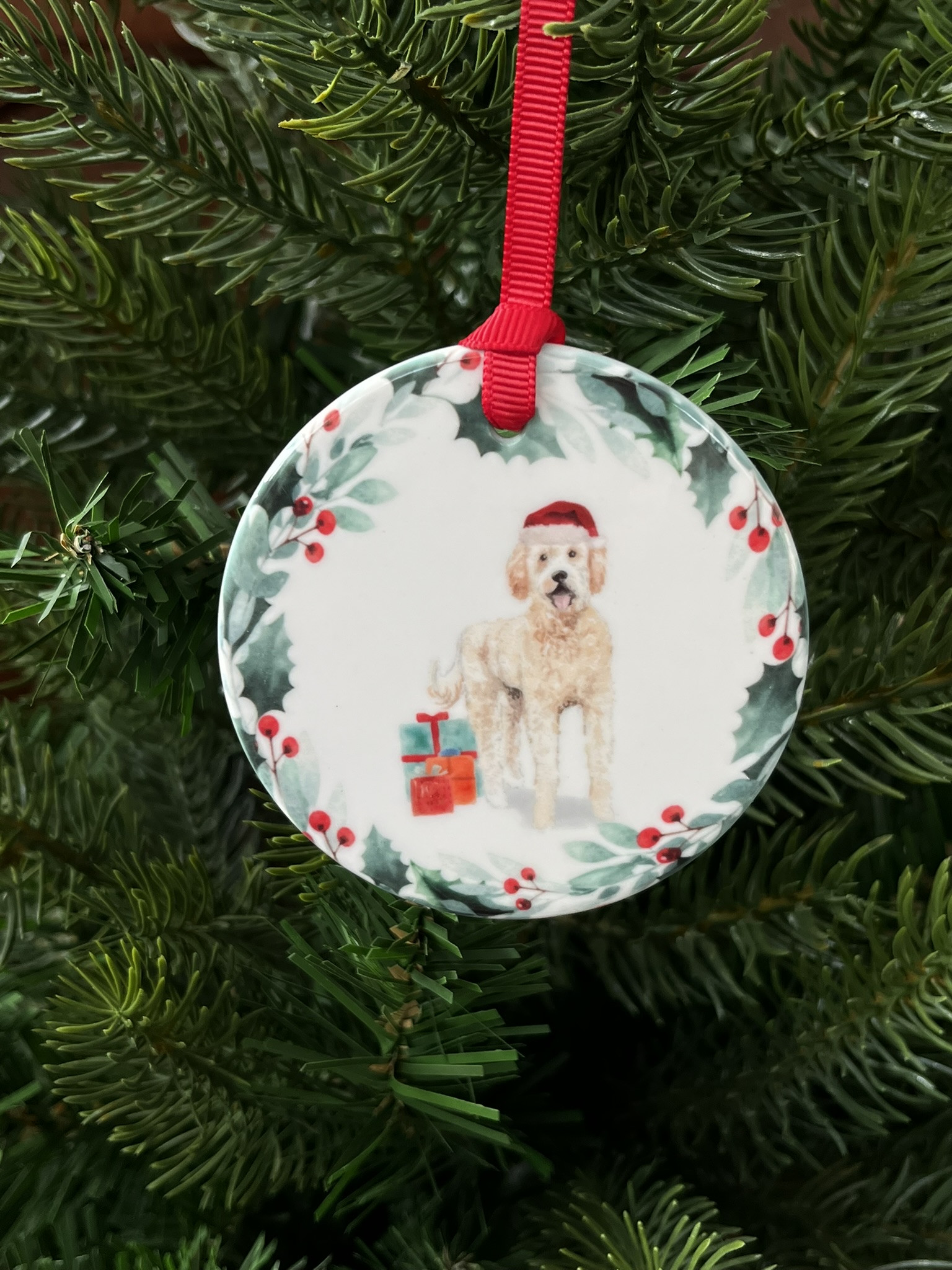 Hanging decoration of a pale coloured Labradoodle wearing a Christmas hat