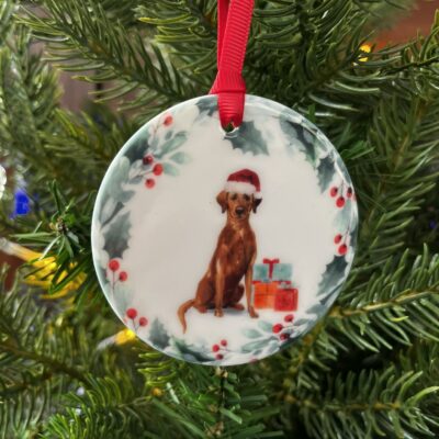 Hanging decoration of a Fox Red Labrador wearing a Christmas hat.